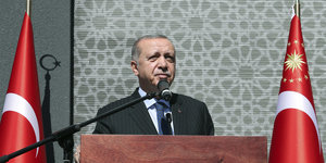 Recep Tayyip Erdogan steht an einem Stehpult, zwischen zwei türkischen Fahnen
