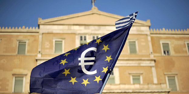 Vor einem Gebäude weht eine EU-Fahne mit dem Euro-Zeichen darauf.
