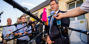 Ein Mann steht vor Mikrofonen. Es ist Markus Söder