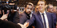 Emmanuel Macron schüttelt eine Hand, sein Bodyguard Alexandre Benalla steht neben ihm