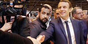 Emmanuel Macron schüttelt eine Hand, sein Bodyguard Alexandre Benalla steht neben ihm