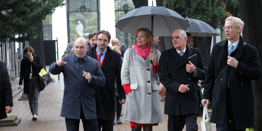 Julia Klöckner umrahmt von mehreren Amtskollegen. Sie hält einen Regenschirm in der Hand