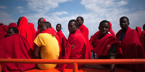 Auf einem Rettungsboot sitzen in Decken gehüllte Flüchtlinge