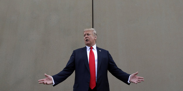 Präsident Trump steht vor einer Mauer