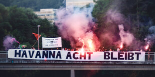 Menschen auf einer Brücke mit Pyro-Feuerwerk und Transparent mit der Aufschrift "Havanna Acht bleibt"