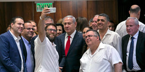Israelischer Regierungschef Benjamin Netanjahu umgeben von knapp einem Dutzend Abgordneter der Koalitionsparteien, die ein Selfie aufnehmen