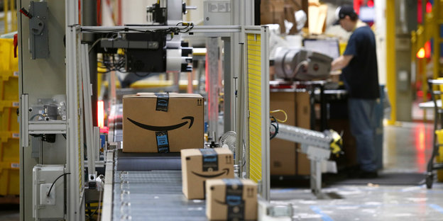 Amazon-Pakete auf einem Fließband unter einem Scanner