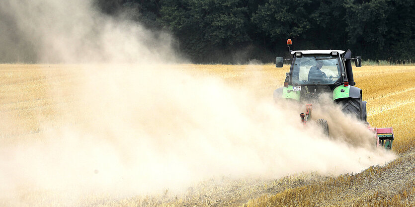 Traktor mit Egge fährt über ein Feld