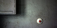 ein Lichtschalter mit rotem Knopf an einer grauen Wand