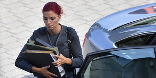 Frau steigt mit Akten aus einem Auto