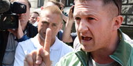 Der britische Rechtsextremist Tommy Robinson hetzt mit erhobenem Zeigefinger vor einer Kamera.