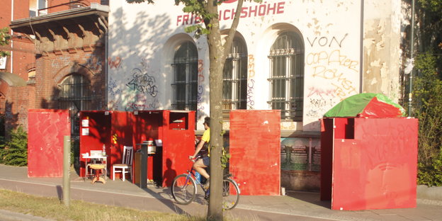 Fünf rote Stahlwürfel stehen auf dem Gehsteig der Landberger Allee und machen auf Leerstand in einer ehemaligen Brauerei aufmerksam