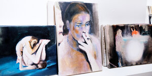 Drei kleine Aquarelle auf einem Regal, darunter eine pornografische Szene und eine rauchende Frau