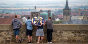 Vier Menschen gucken über ein Mäuerchen auf Erfurt hinunter