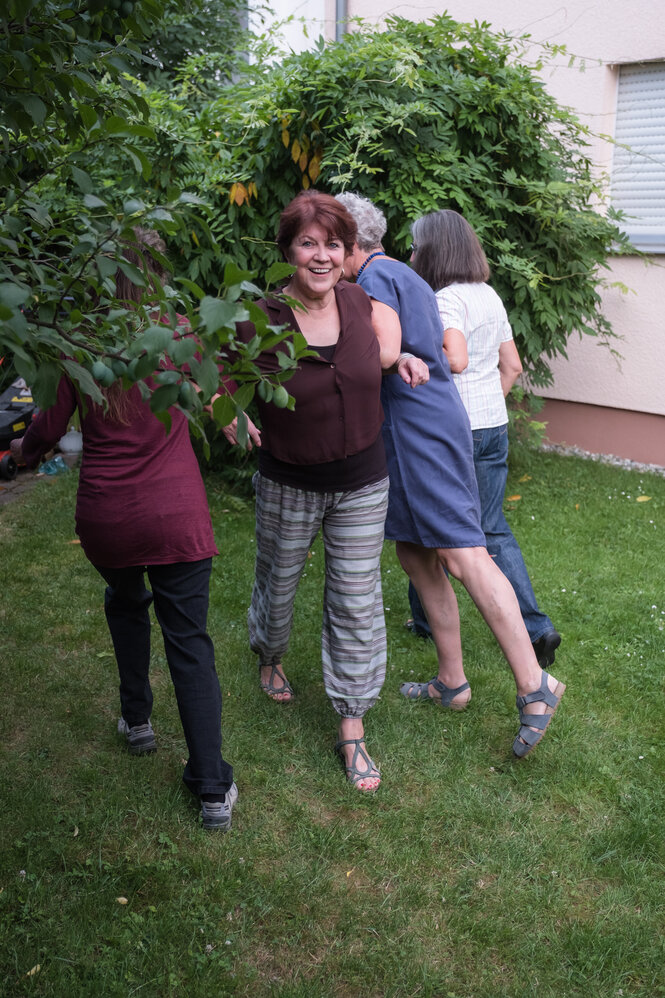 Vier Frauen im Garten in der Nähe eines Baumes, nur eine dreht der Kamera das Gesicht zu