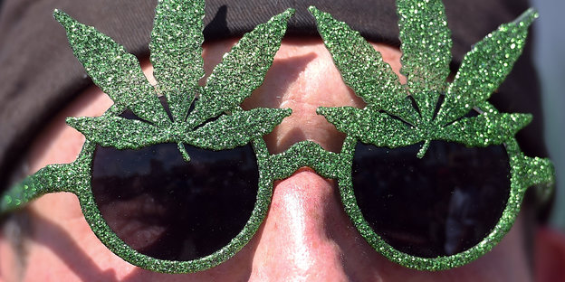 Mann mit Sonnenbrille, deren Umfassung mit zwei Marihuanablättern verziert ist