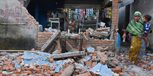 Eine Frau mit Kind inmitten den Trümmern eines Lebensmittelladens