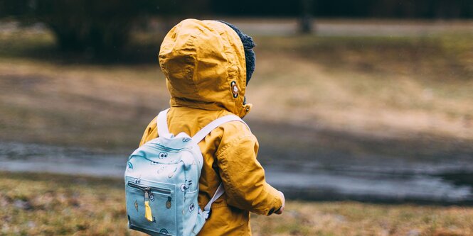 Ein Kind mit Rucksack und Jacke