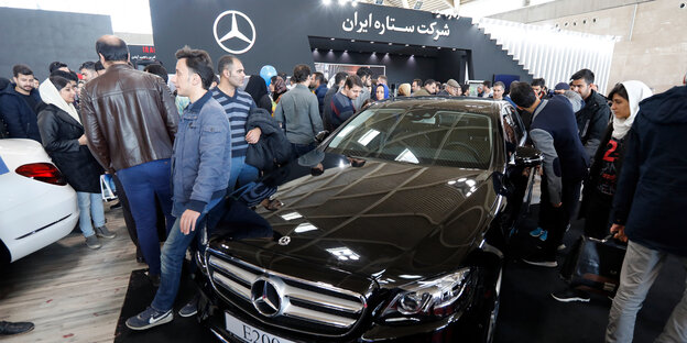 Besucher einer Automesse begutachten einen Mercedes