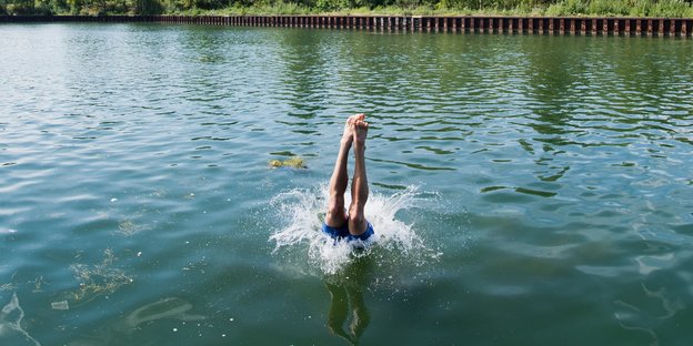 Die Beine eines Mannes ragen aus dem Wasser, in das er gerade mit einem Kopfsprung eingetaucht ist