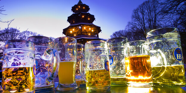 Der Chinesische Turm in München im Sonnenuntergang. Halb ausgetrunkene Maßkrüge im Vordergrund
