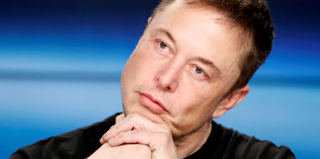 Elon Musk stützt den Kopf nachdenklich auf die Hände
