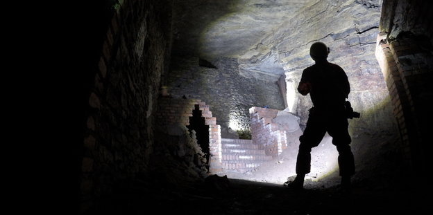 Ein Mann steht vor einem zugemauerten Aufgang in den Gertrudenberger Höhlen.