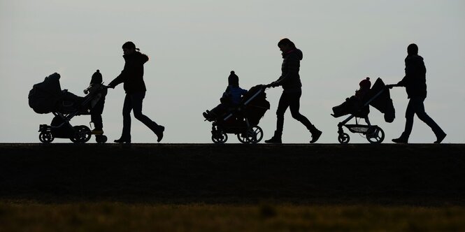 Drei Kinderwagen werden von vier Personen geschoben