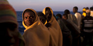 Gerettete afrikanische Flüchtlinge, in gelbe Decken gehüllt