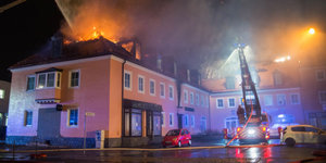 Ein Feuerwehrfahrzeug steht in Bautzen (Sachsen) vor einem brennenden Haus. In einer geplanten Flüchtlingsunterkunft war in der Nacht ein Feuer ausgebrochen.