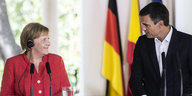 Merkel und Sánchez stehen vor Mikrofonen und gucken sich an