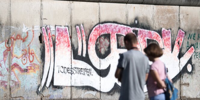 Zwei Menschen stehen vor einer Mauer