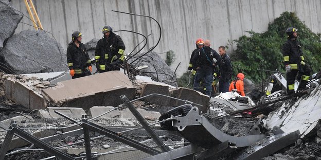 Rettungskräfte stehen in den Trümmern der Brücke