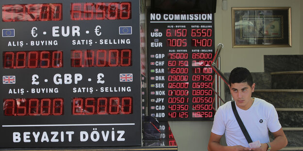 Mann vor Anzeigetafel mit den Wechselkursen in Türkei