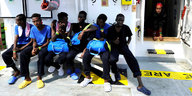 Sechs Männer, gerettete Flüchtlinge, sitzen an Bord eines Schiffes