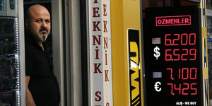 Mann vor Anzeigetafel mit den Wechselkursen in Türkei