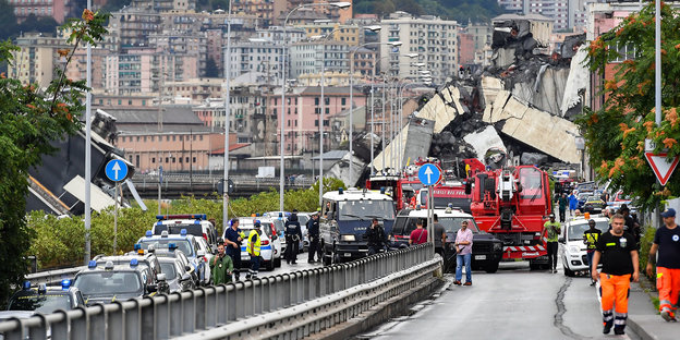 Feuerwehrwagen, Polizeiautos und Einsatzkräfte sind vor der teilweise eingestürzten Autobahnbrücke Ponte Morandi zu sehen