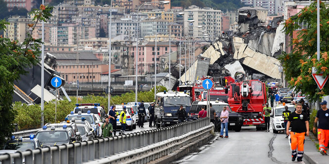 Feuerwehrwagen, Polizeiautos und Einsatzkräfte sind vor der teilweise eingestürzten Autobahnbrücke Ponte Morandi zu sehen