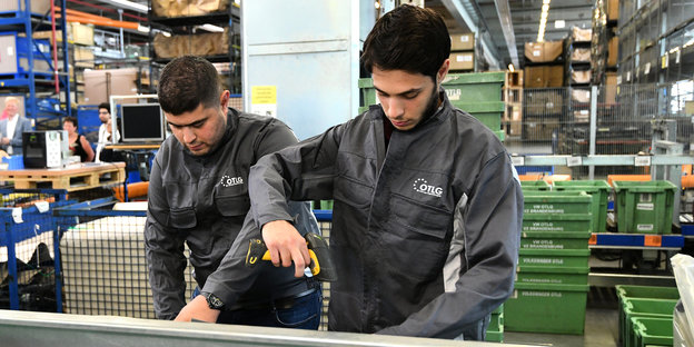 Zwei junge Männer in Arbeitsoveralls erfassen im Vertriebszentrum Brandenburg der Volkswagen OTLG eingehende Ware.