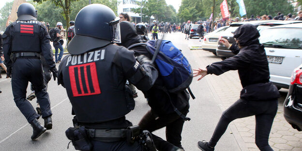 Ein Polizist schlägt einen Demonstranten mit einem Schlagstock.