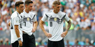 Özil, Draxler und Kroos stehen auf dem Fußballplatz nebeneinander
