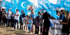 Eine Demonstrantion mit blauen, uigurischen Flaggen