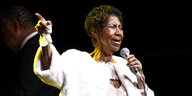 Aretha Franklin hält ein Mikrofon in der Hand und singt