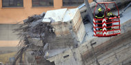 Feuerwehrleute entfernen Trümmer der teilweise eingestürzten Morandi Autobahnbrücke im italienischen Genua