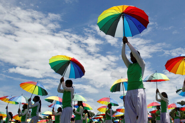 Indische Mädchen halten regenbogenfarbene Regenschirme hoch