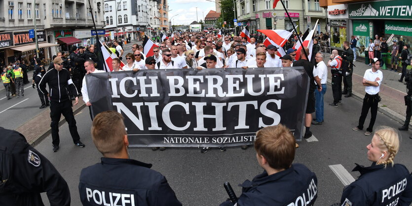 Neonazis stehen hinter einem Plakat mit der Aufschrift "Ich bereue nichts"