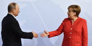 Der russische Präsident Putin und Kanzlerin Angela Merkel geben sich die Hand
