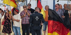 Teilnehmer einer Demonstration der islamfeindlichen Pegida-Bewegung stehen anlässlich des bevorstehenden Besuchs von Bundeskanzlerin Merkel (CDU) im Sächsischen Landtag an einer Straßenkreuzung