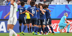 Im Hintergrund jubeln japanische Fußballerinnen, im Vordergrund geht eine traurige deutsche Spielerin