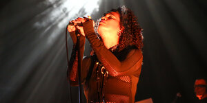 Die Sängerin Neneh Cherry singt in ein Mikrofon